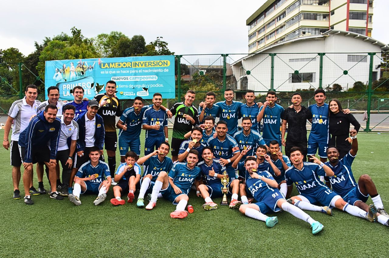 Equipo campeón de fútbol universitario posando con sus medallas y trofeo