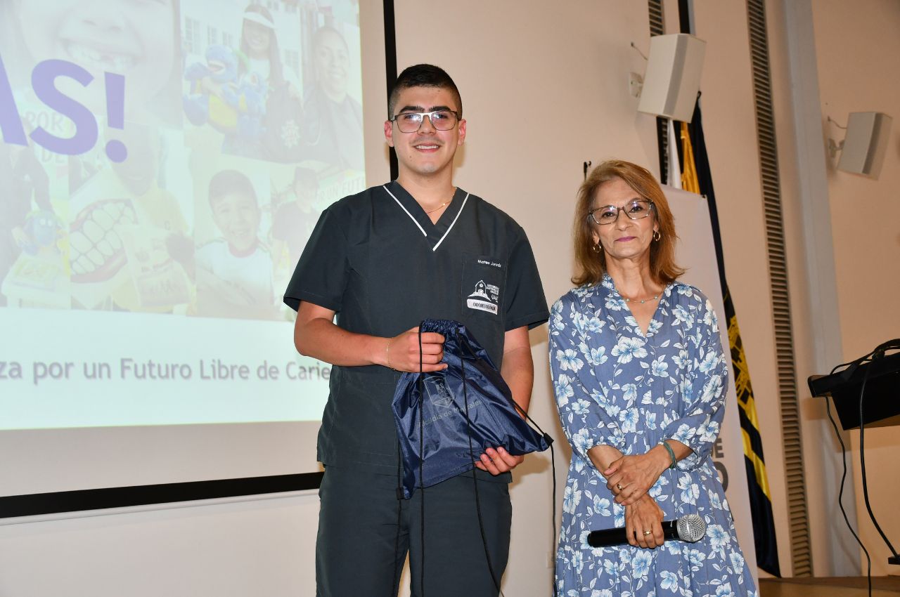 La profesora Luz Dary Joya Rodríguez entrega un premio a uno de los estudiantes de Odontología.