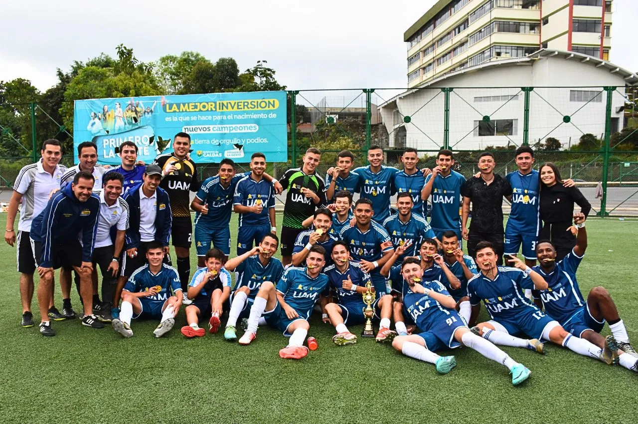 Equipo campeón de fútbol universitario posando con sus medallas y trofeo